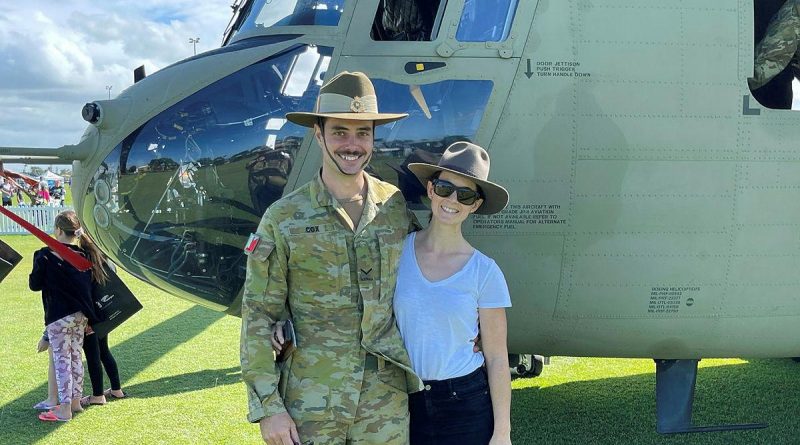 Lance Corporal Brendan Cox and his partner, Holly Fowler, stand in front of an Australian Army CH47F Chinook helicopter.