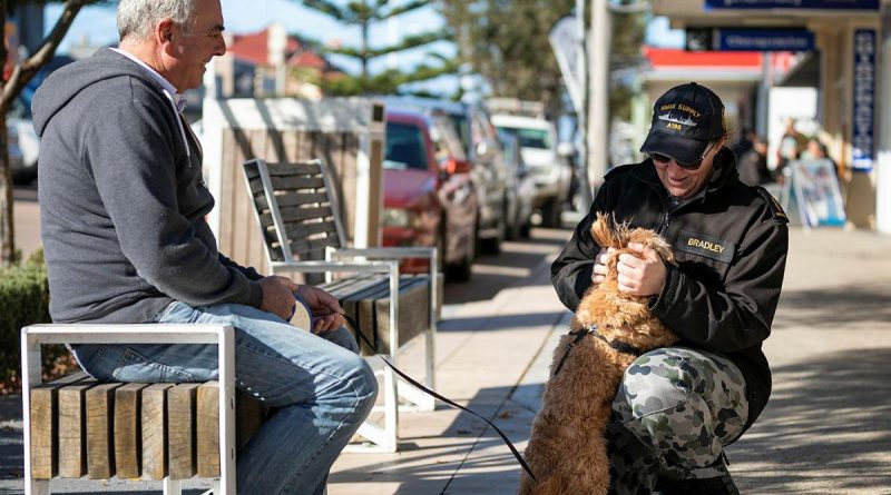 Able Seaman Tegan Bradley pats an Eden resident’s dog during the ship’s company’s walk into the NSW town during a port visit. Story by Acting Sub Lieutenant Jack Meadows. Photo by Leading Seaman Daniel Goodman.