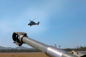 An Australian Army Tiger Armed Reconnaissance Helicopter flies past an M777 Howitzer at Shoalwater Bay Training Area, Talisman Sabre 2021. Photo by Warrant Officer Class 2 Max Bree.