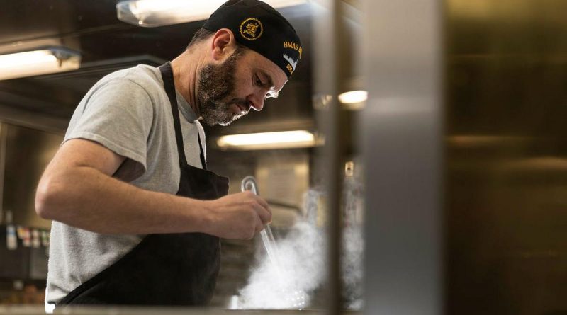 Commanding Officer HMAS Brisbane Commander Aaron Cox, cooks 'midnighters' for his crew in the galley, during Exercise Talisman Sabre. Story and photo by Leading Seaman Daniel Goodman.