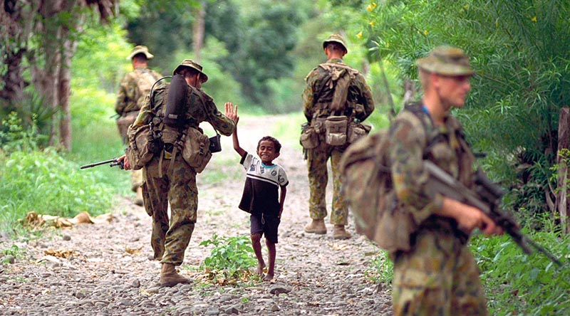 Boy greets Aussie soldiers on patrol in East Timor, Photo by Corporal Brian Hartigan.