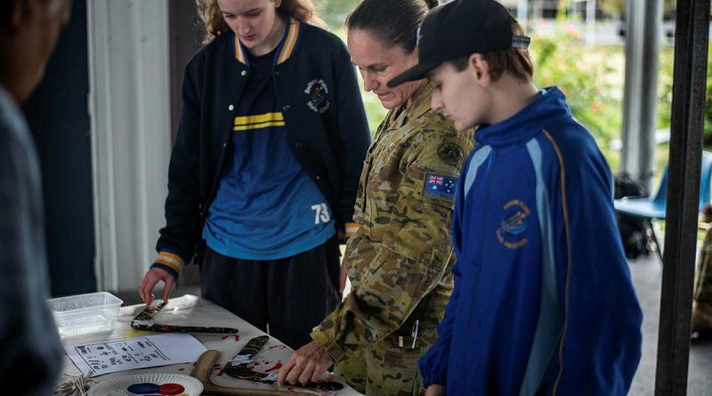 Warrant Officer Class One Kelly Hammant instructs students from Redbank Plains State High School how to paint boomerangs in traditional styles. Story by Captain Jesse Robilliard. Photo by Private Jacob Hilton.