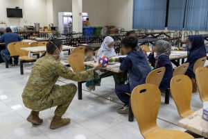 Camp Commandant, Major Joel Bell gives a ball to an evacuee in the mess hall of the temporary camp, in Australia’s main operating base in the Middle East. Photo by Leading Aircraftwoman Jacqueline Forrester.