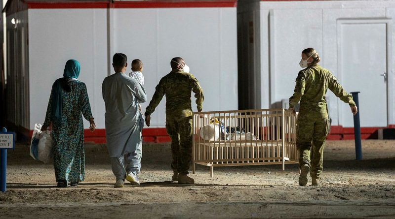 Signaller Charbal Nunes of 145 Signal Squadron (centre) and Corporal Nikkiska McGlashan, 3 Combat Signal Regiment (right) help a family transport a cot to their room at the temporary camp. Story by Lieutenant Max Logan. Photo by Leading Aircraftwoman Jacqueline Forrester.