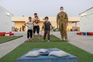 Lieutenant Max Logan (right) plays with Afghanistan evacuees at the temporary camp in Australia's main operating base in the Middle East. Photo by Leading AIrcraftwoman Jacqueline Forrester.