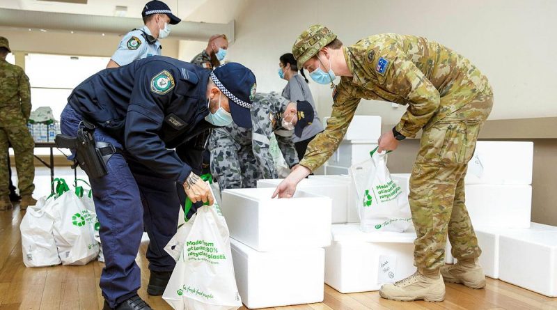 NSW Police and ADF members prepare to deliver pre-made meals as part of care packages given to homes in the Fairfield community in Sydney. Story by Lieutenant Commander John Thompson. Photo by Corporal Dustin Anderson.