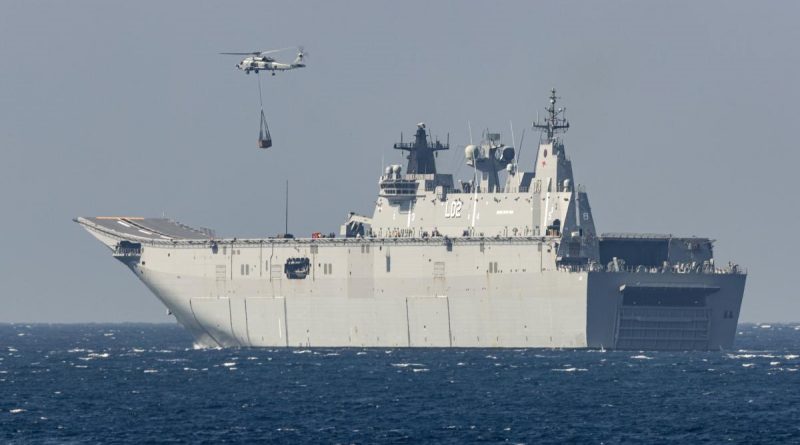 HMAS Anzac's embarked MH-60R collects a desalination plant from HMAS Canberra for delivery to the Balinese island of Nusa Lembongan during IPE21. Photo by Leading Seaman Leo Baumgartner.