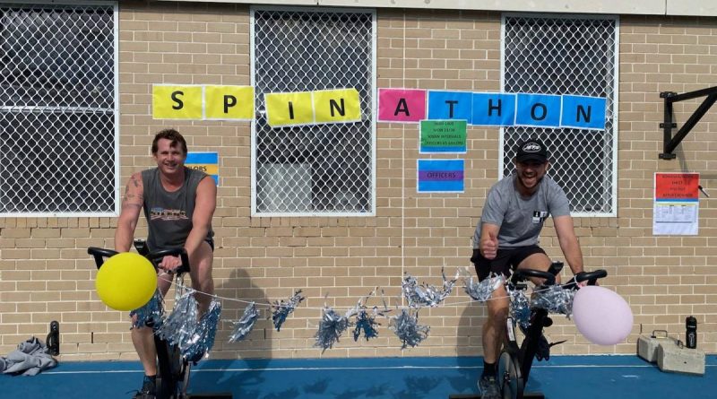 Petty Officer Simon Taylor, left, and Lieutenant Commander James Knight compete in the HMAS Watson spin-a-thon fundraiser for Dry July. Story by Lieutenant Kiz Welling-Burtenshaw.