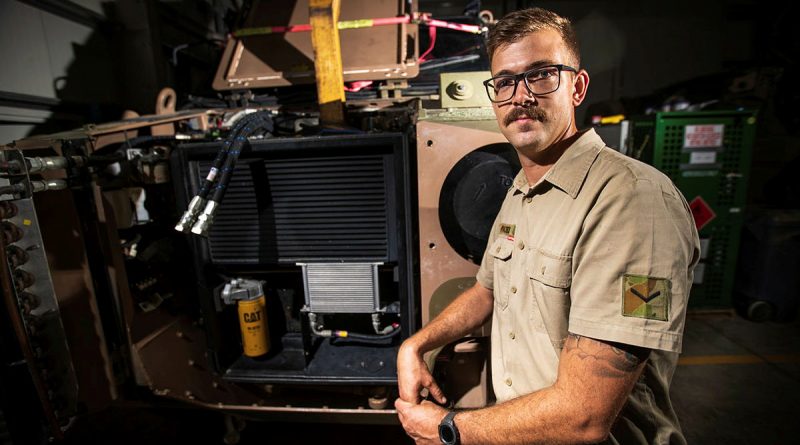 Australian Army Vehicle Mechanic Lance Corporal Timothy Pates in front of a protective mobility vehicle prepared for deep clean at Australia's main operating base in the Middle East. Photo by Sergeant Glen McCarthy.