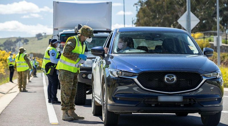 Lance Corporal Mancell Laidler, of Joint Task Group 629.9, inspects the licence of a motorist at the ACT Federal Highway border-control point during Operation COVID-19 Assist. Photo by Corporal Jarrod McAneney.