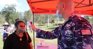 Malabugilmah resident Latia Williams has her temperature taken by Leading Aircraftman Joel Forster at a pop-up COVID-19 vaccination centre.