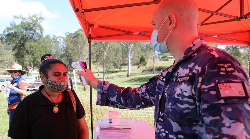 Malabugilmah resident Latia Williams has her temperature taken by Leading Aircraftman Joel Forster at a pop-up COVID-19 vaccination centre.