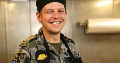 Lance Corporal Christopher Lyne puts on his apron on before preparing meals in HMAS Canberra's galley for the Ship's Company and embarked forces on the way to Exercise Talisman Sabre 21. Photo by Leading Seaman Nadev Harel.