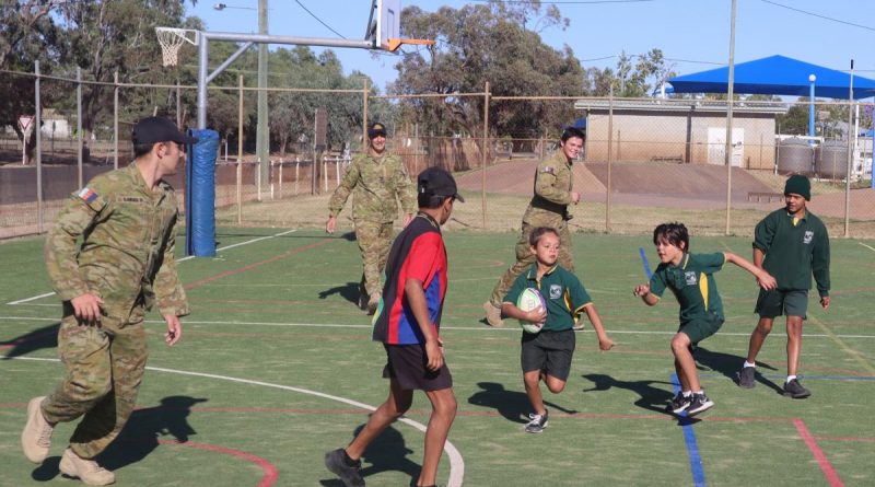 Private Robert Bayley, Corporal Jake Cobb and Private Harrison Britt play touch football with children at the Cunnamulla Breakfast Club. Story by Captain Pete Conrad .