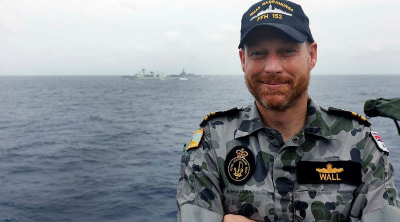 HMAS Warramunga's principal warfare officer and former Royal Canadian Navy officer, Lieutenant Commander Stephen Wall, with his former ship HMCS Winnipeg and HMAS Brisbane in the background. Photo by Petty Officer Yuri Ramsey.