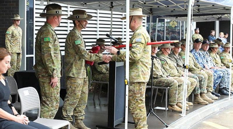 Outgoing Commander 1st Division Major General Jake Ellwood, centre, accepts the 1st Division pennant from Regimental Sergeant Major Warrant Officer Class One Michael Landy during the command handover parade. Story by Lieutenant Simon Hampson. Photo by Sergeant Kerry Uilderks.