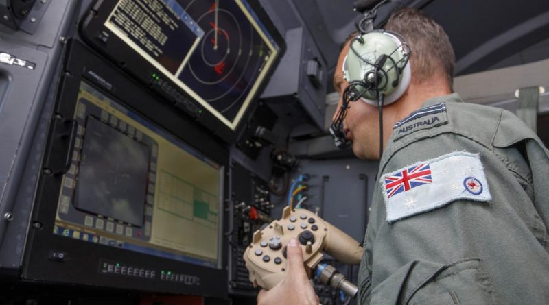 RAAF combat systems officer Flight Lieutenant Cameron McKinnon works at the C-130J Hercules aircraft's augmented crew station to capture imagery of the damage in Tonga. Story by Eamon Hamilton. Photo by Sergeant David Gibbs.