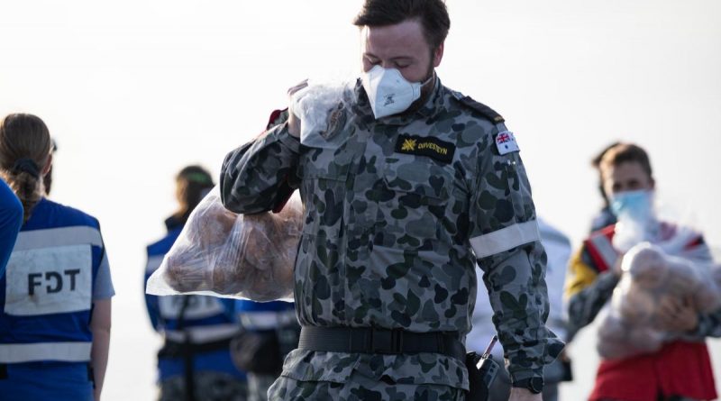 Navy sailor Seaman combat systems operator Mark Duivesteyn carries fruit gifted from the Tonga onboard HMAS Adelaide during Operation Tonga Assist 2022. Story by Lieutenant Brendan Trembath. Photo by Leading Seaman David Cox.