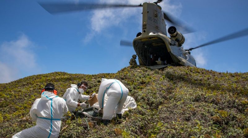 An Army CH-47F Chinook helicopter lands on Kao Island, allowing three Tongan technicians to unload equipment to repair telecommunications equipment. Story by Lieutenant Brendan Trembath. Photo by Petty Officer Christopher Szumlanski..