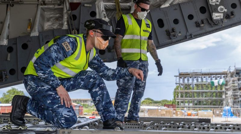 Aircraftsman Sam Schmidt, left, guides a forklift operator while unloading a C-17A Globemaster III aircraft at Honiara International Airport, Solomon Islands. Story by Captain Peter March. Photo by Corporal Jarrod McAneney.