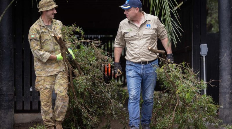 Private Rory Khochoba (left) from 6th Battalion, Royal Australian Regiment, working alongside the Lord Mayor of Brisbane, Adrian Schrinner, clearing debris from flood-damaged houses in Windsor, Brisbane. Story by Lieutenant Geoff Long. Photo by Corporal Jonathan Goedhart.