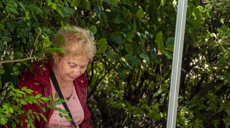 Army Corporal Sebastian Evens (odd camera - right) from 6th Battalion, Royal Australian Regiment, applies a bandage to St Lucia resident Ms Ann Mckenzie. Story by Lieutenant NIc Hawkins. Photo by Corporal Nicole Dorrett.