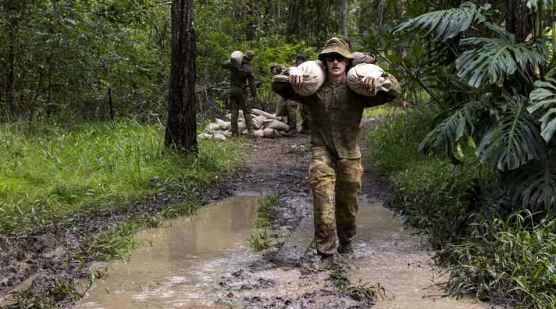An Army officer from 7th Brigade carries sandbags across a flooded section of trail to repair flood-damaged access tracks in Imbil, Queensland, as part of Operation Flood Assist 2022. Story by Flight Lieutenant Tanya Carter. Photo by Corporal Julia Whitwell.