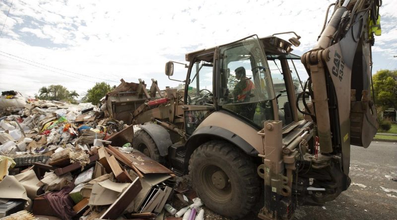 An Army soldier uses a backhoe to clear flood-damaged household goods from a street in Lismore, as part of Operation Flood Assist 2022. Story and photo by Warrant Officer Class Two Max Bree.