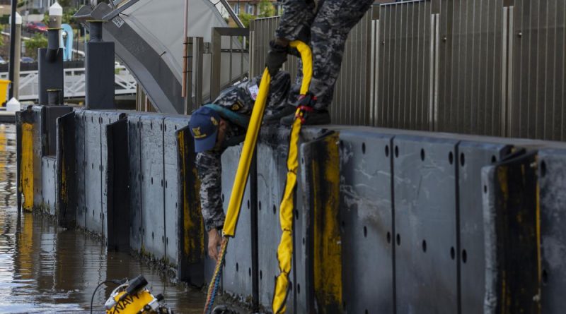 Navy divers Chief Petty Officer Cameron Schmid, right, and Able Seaman Jordan Bitolkoski, centre, assist Able Seaman Jake Phillips as he surveys ferry terminals pylons along the Brisbane River. Story by Private Jacob Joseph. Photo by Corporal Julia Whitwell.