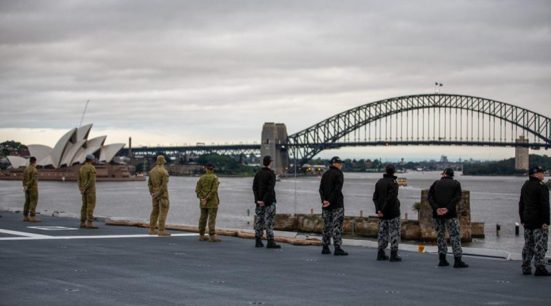 Australian Defence Force personnel on HMAS Adelaide line the flight deck as the ship returns to her home port of Fleet Base East in Sydney following a deployment on Operation Tonga Assist 2022. Story by Lieutenant Max Logan. Photo by Petty Officer Christopher Szumlanski.