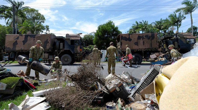 Australian Army soldiers from 6th Battalion, Royal Australian Regiment, collect flood-damaged household items for loading onto a truck as they clear a street in Chinderah, New South Wales. Story by Captain Annie Richardson. Photo by Warrant Officer Class Two Max Bree.