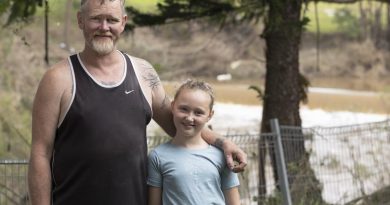 Casino local Terry Lloyd with his youngest daughter stand in his daughter Clarisa's Casino, New South Wales, backyard with the Richmond River, which flooded the house, in the background. Story by Captain Annie Richardson. Photo by Corporal Sagi Biderman.