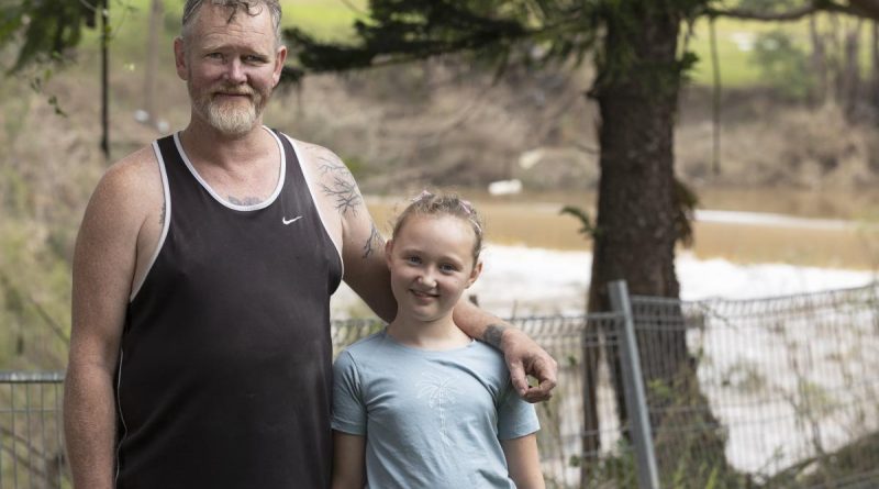 Casino local Terry Lloyd with his youngest daughter stand in his daughter Clarisa's Casino, New South Wales, backyard with the Richmond River, which flooded the house, in the background. Story by Captain Annie Richardson. Photo by Corporal Sagi Biderman.