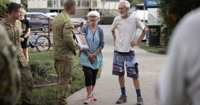 Australian Army officer Lieutenant Brook Wright (centre left) from 8th/9th Battalion, Royal Australian Regiment, presents Broadwater, locals Annette and Trevor Walsh with a unit flag. Story by Major Jesse Robilliard. Photo by Corporal Jonathan Goedhart.