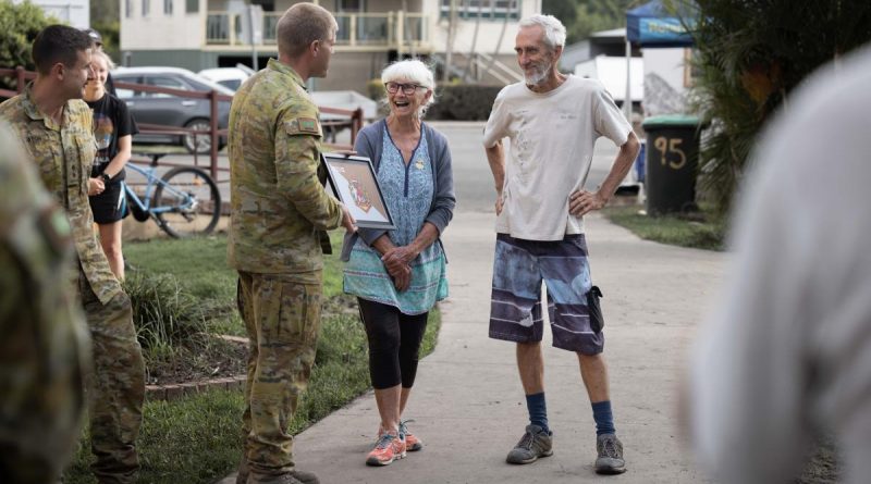 Australian Army officer Lieutenant Brook Wright (centre left) from 8th/9th Battalion, Royal Australian Regiment, presents Broadwater, locals Annette and Trevor Walsh with a unit flag. Story by Major Jesse Robilliard. Photo by Corporal Jonathan Goedhart.