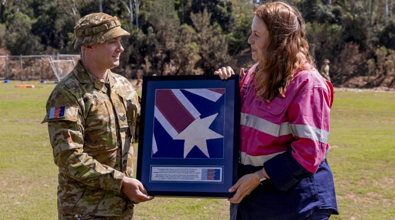 Sergeant Brad Wilson presents an Australian National Flag found in flood debris at Brassall to Ipswich City Mayor Teresa Harding during her visit to Colleges Crossing recreation reserve in Ipswich. Story by Captain Taylor Lynch. Photo by Corporal Nicole Dorrett.