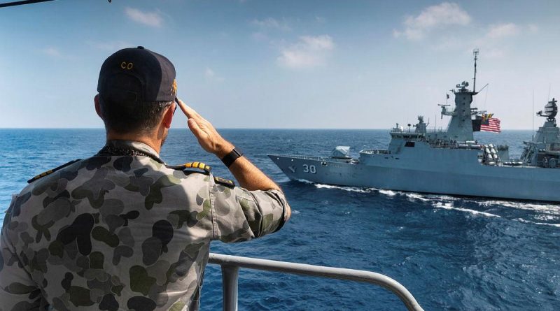 Commanding Officer HMAS Arunta Commander Samuel Woolrych salutes as Royal Malaysian Navy frigate KD Lekiu sails past. Story by Lieutenant Commander Andrew Herring. Photo by Leading Seaman Sittichai Sakonpoonpol.