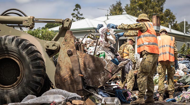 Australian Army soldiers from the 5th Engineer Regiment use earth-moving equipment to clear debris from a flood-affected house in Lismore, New South Wales, during Operation Flood Assist 2022. Photo by Corporal Jonathan Goedhart.