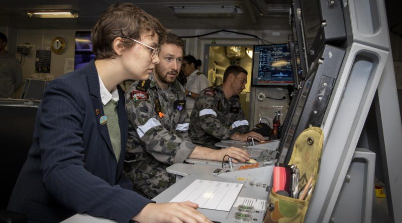 Able Seaman Hamish Scott demonstrates HMAS Sydney's marine technical console to Madeleine Devitt during the Indo Pacific 2022 conference in Sydney. Story by Lieutenant Yvette Goldberg. Photo by Leading Seaman Matthew Lyall.