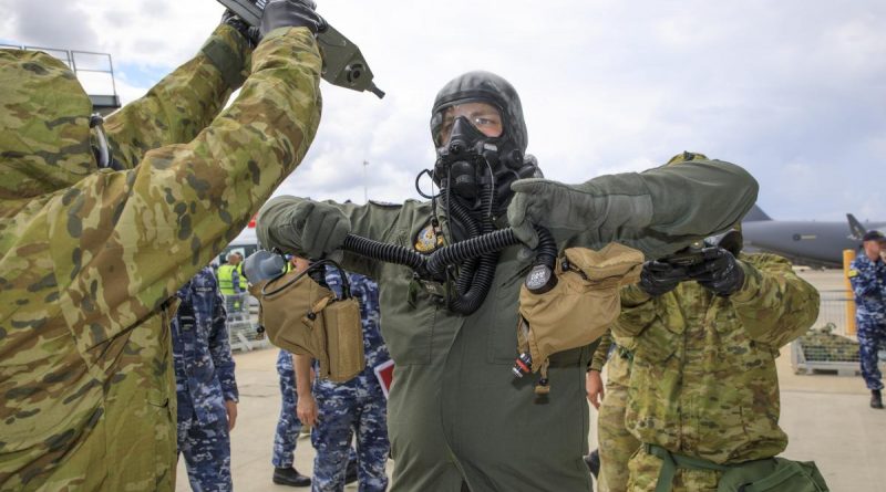 Aviators from No 381 and No. 1 Security Forces Squadrons guide a pilot with protective clothing through the decontamination processes during Exercise Toxic Safari at RAAF Base Amberley. Story by Flight Lieutenant Robert Hodgson. Photo by Corporal Brett Sherriff.
