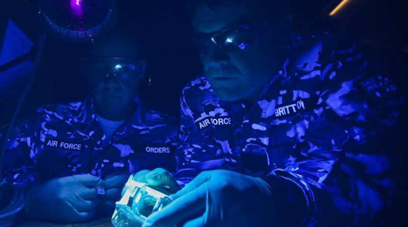Corporal Daniel Orders (left) and then Sergeant Geoff Britton conduct a fluorescent liquid penetrant test on an aircraft component under ultraviolet light in 2016. Story by Squadron Leader Barrie Bardoe. Photo by Corporal Brenton Kwaterski.