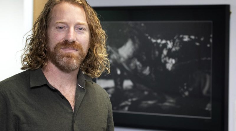 Retired Australian Army officer and artist Mike Armstrong stands in front of a photograph he produced as part of a photographic exhibition titled 'Voices of Veterans' at the National Press Gallery in Canberra. Story by Sergeant Matthew Bickerton.