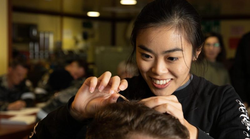 Macquarie University researcher Madison Kho takes a hair sample from a HMAS Canberra crew member to measure cortisol levels. Story by Lieutenant Nancy Cotton. Photo by Leading Seaman Matthew Lyall.