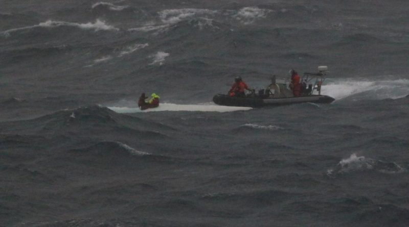 HMAS Brisbane’s rigid hulled inflatable boat crew rescues the stricken mariners from the hull of their upturned yacht off the coast of Wollongong. Photo supplied.