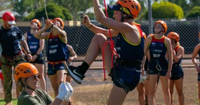 An AFLW Adelaide Crows player climbs a rope ladder with Army Sapper Abbey Patzel holding it steady during their visit to Robertson Barracks as part of their pre-season training camp. Story by Sergeant Matthew Bickerton. Photo by Captain Peter March.
