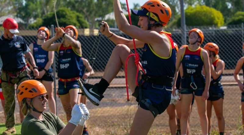 An AFLW Adelaide Crows player climbs a rope ladder with Army Sapper Abbey Patzel holding it steady during their visit to Robertson Barracks as part of their pre-season training camp. Story by Sergeant Matthew Bickerton. Photo by Captain Peter March.