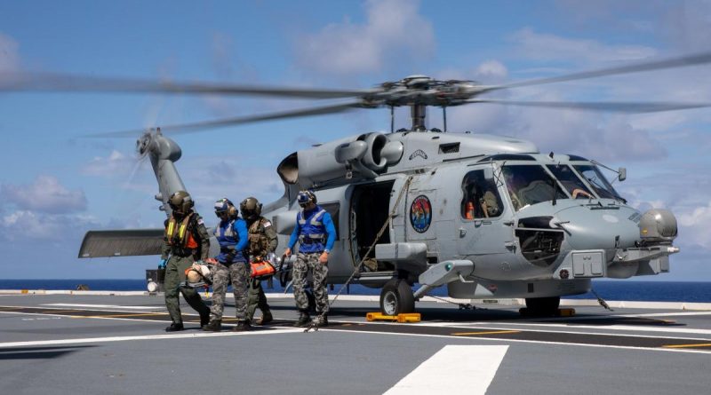 Royal Australian Navy medical officers Commander Robert Turner and Lieutenant Cody Nash transfer a simulated casualty from a MH-60R Seahawk during a training exercise on board HMAS Canberra. Story by Lieutenant Nancy Cotton. Photo by Petty Officer Christopher Szumlanski.