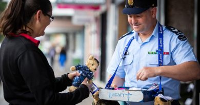 Flight Sergeant Geoff McLaughin, from No. 77 Squadron at RAAF Base Williamtown, sells a Legacy bear to Louise Neider in Newcastle during Legacy Week. Story and photo by Corporal Melina Young.