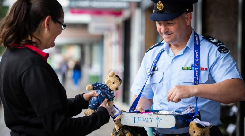 Flight Sergeant Geoff McLaughin, from No. 77 Squadron at RAAF Base Williamtown, sells a Legacy bear to Louise Neider in Newcastle during Legacy Week. Story and photo by Corporal Melina Young.
