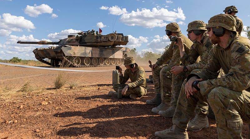 Australian soldiers watch a 1st Armoured Regiment, Royal Australian Armoured Corps, M1 Abrams tank drive past during a live-fire demonstration on Exercise Predators Run at Mount Bundey Training Area, NT. Photo by Corporal Jacob Joseph.